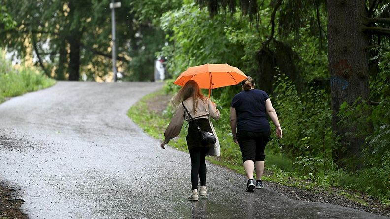 Kaksi ihmistä kävelevät sateessa Espoossa.