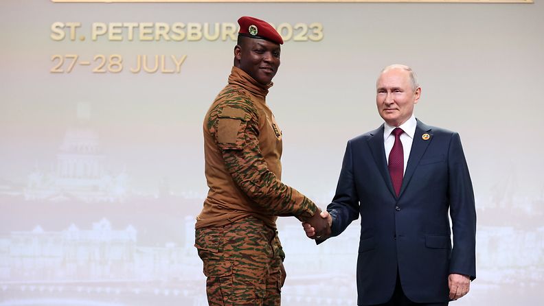 Maastopukuinen Burkina Fason presidentti Ibrahim Traore kättelee Putinia hymyillen.