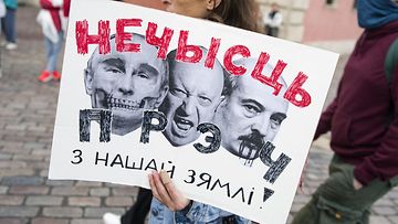 Mielenosoittajan kyltissä Putin, Lukashenka ja Prigozhin.