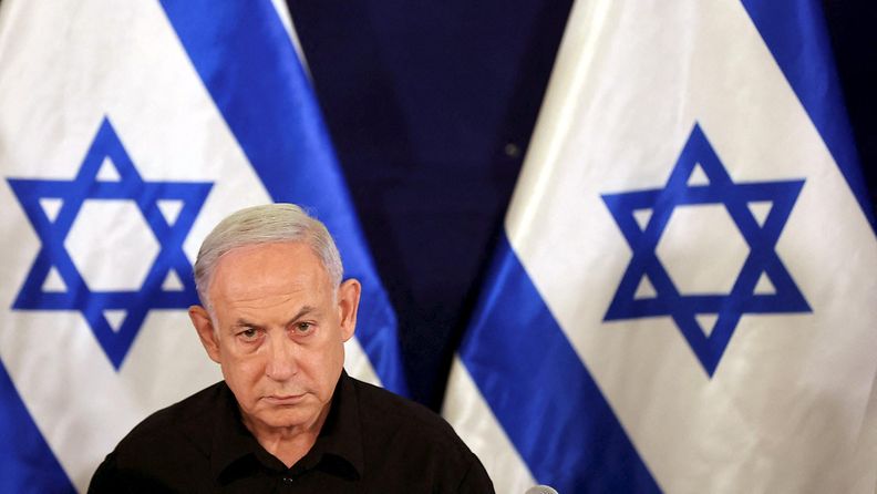 Netanjahu Israelin lipun edessä.