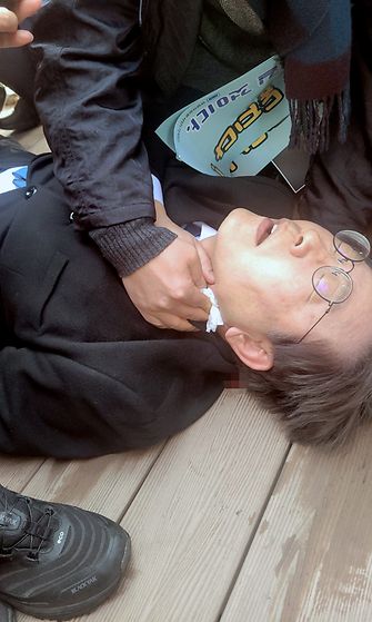Lee Jae-myung, leader of the main opposition Democratic Party, lies down after he was stabbed by an assailant on the left side of his neck during a visit to the construction site