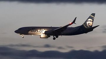 AOP Kuvituskuvan Alaska Airlinesin Boeing 737-800 -lentokone laskeutumassa iltahämärissä Washingtonin kansalliselle lentokentälle Yhdysvalloissa.