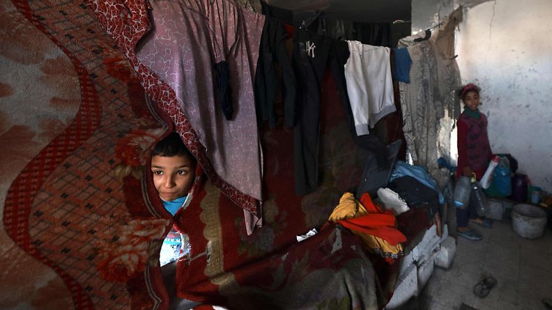 LK 17.1.2024 Palestiinalaislapset suojautuivat perheensä kanssa Israelin pommituksilta vaurioituneeseen rakennukseen Rafahissa Gazan eteläosassa 17. tammikuuta 2024.