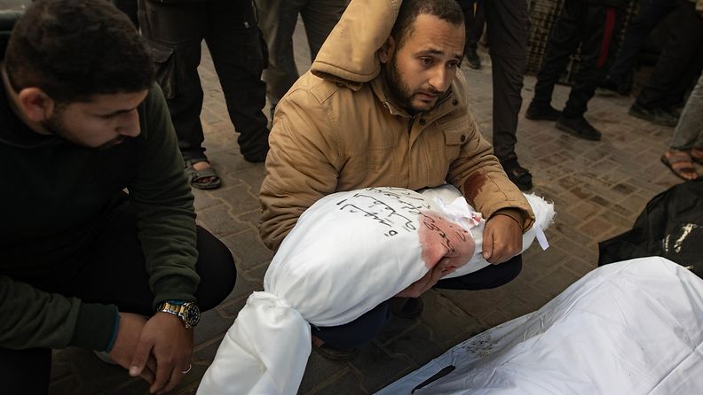 Mies piteli nuoren tytön kankaisiin käärittyä ruumista sylissään Rafahissa 21. helmikuuta 2024.