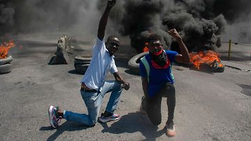 LK 14.3.2024 Mielenosoittajat reagoivat, kun renkaat palavat kadulla mielenosoituksessa pääministeri Ariel Henryn eron jälkeen Port-au-Princessä Haitissa 12. maaliskuuta 2024.