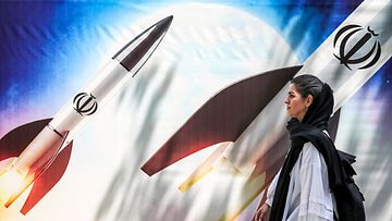 Nainen ohjuskuvan edessä Iranissa 15. huhtikuuta.