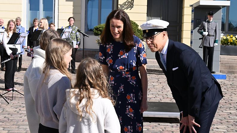 LK: Folkhälsanin Vappukukka-rintamerkki luovutetaan presidentti Alexander Stubbille ja hänen puolisolleen Suzanne Innes-Stubbille Presidentinlinnan pihalla Helsingissä vappupäivänä 1. toukokuuta 2024.