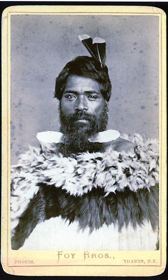AOP Tunnistamaton maorimies, jolla on kaksi huian pyrstösulkia hiuksissaan ja päällään höyhenviitta (Uusi-Seelanti Päiväys 1872–86).