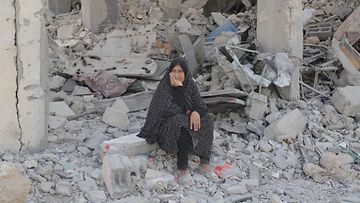 Nainen istui tuhoutuneiden rakennusten raunioiden päällä Gaza Cityssä torstaina.