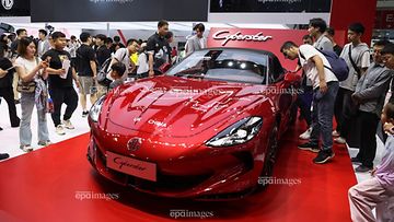 Ihmiset katselevat punaista MG Cyberster -sähköautoa Pekingin kansainvälisessä autonäyttelyssä huhtikuussa.