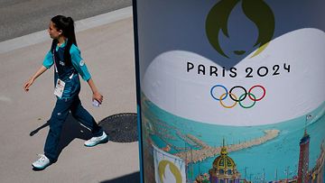 LK 20.7.2024 Vapaaehtoinen käveli Pariisin 2024 olympialogon edessä Pariisin 2024 olympialaisten ja paralympialaisten urheilijakylässä Saint-Denis'ssä Pariisin pohjoispuolella 18. heinäkuuta 2024.